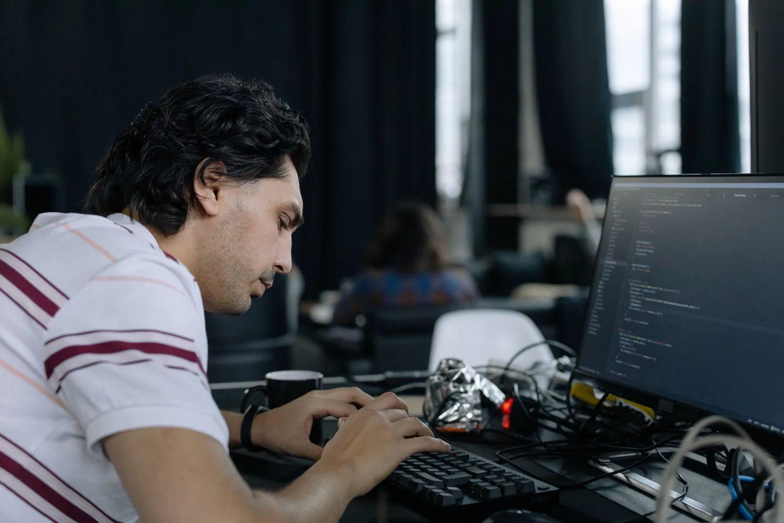 A developer focused on code across dual monitors in a modern office.