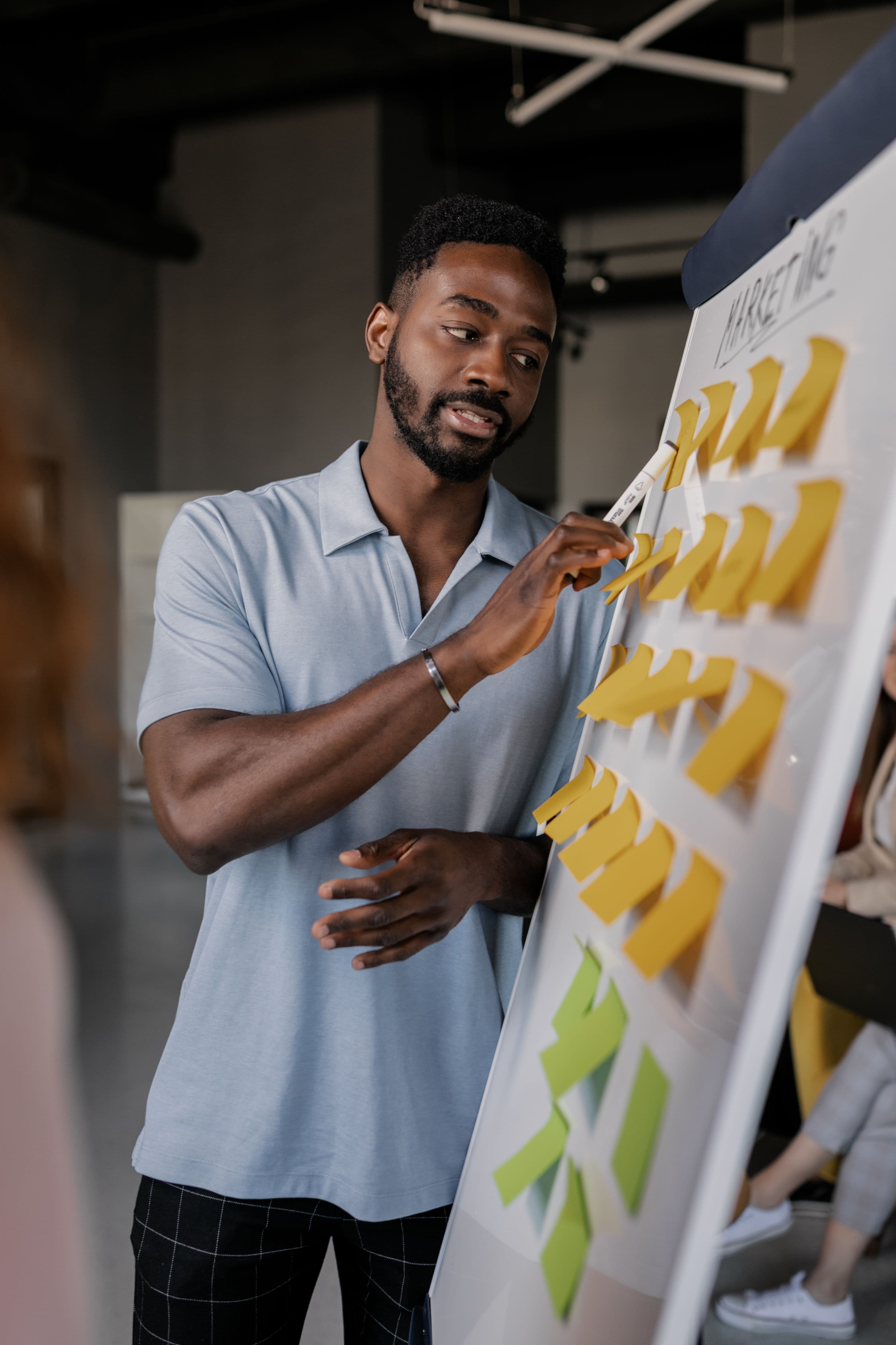 A man arranging separate sticky notes across a wall while planning.