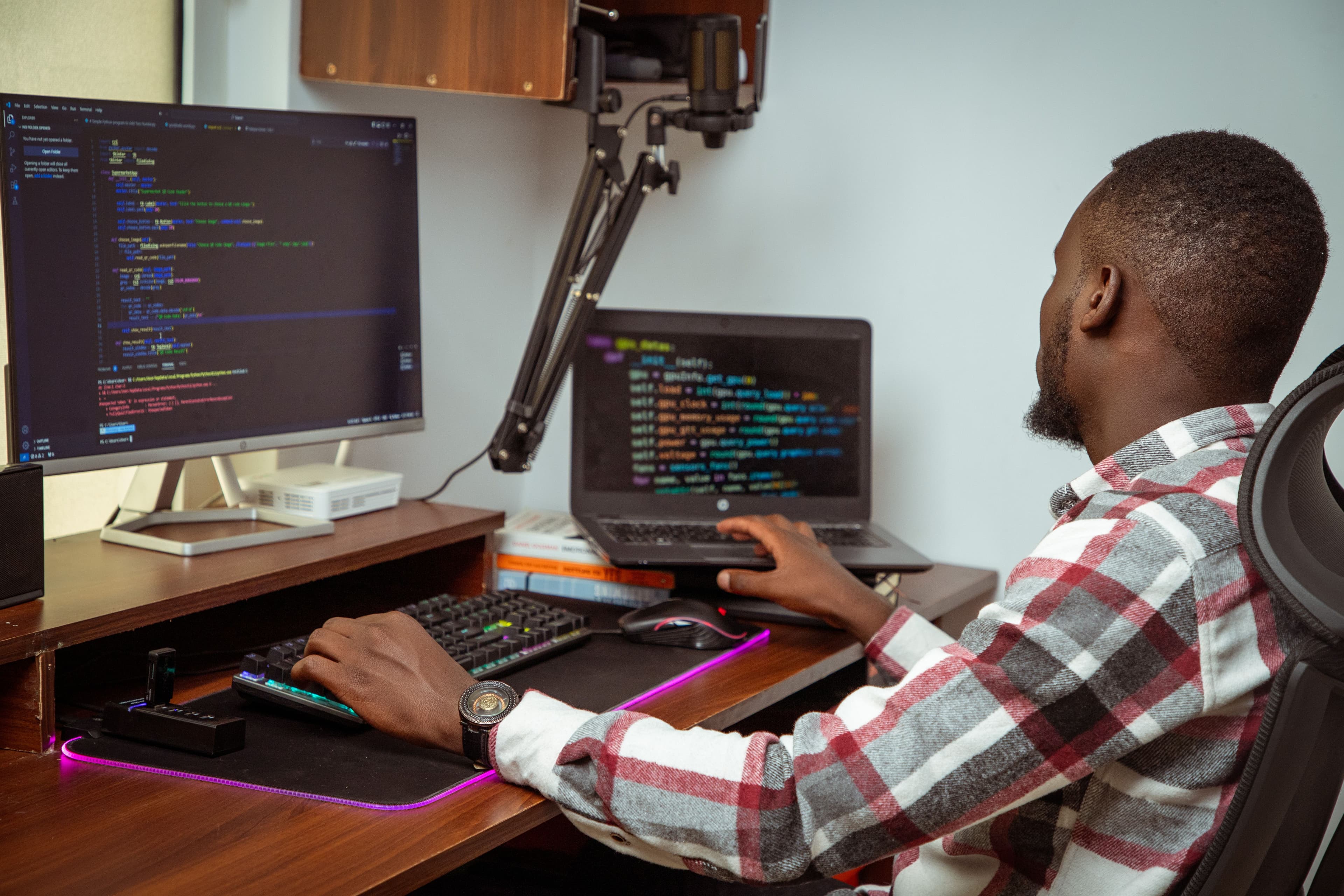 A developer reviewing code across two screens at a home workstation.